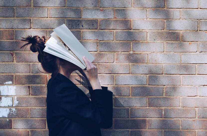 Vrouw met boek voor haar gezicht